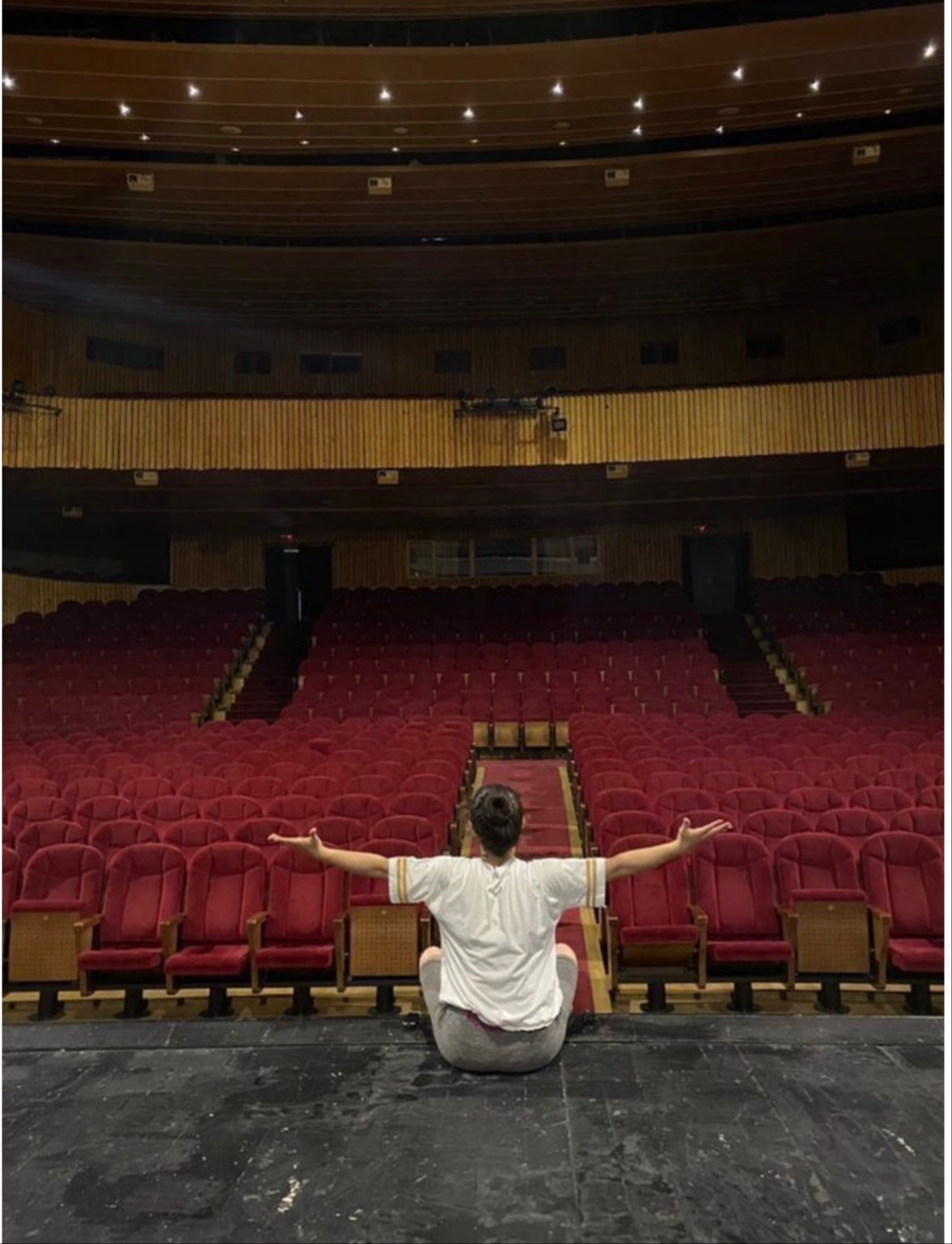 An actor on stage, arms open to an empty auditorium