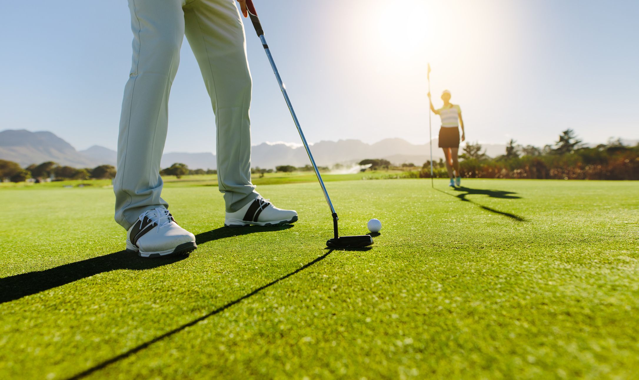 Golfer die een putt voorbereidt op een zonnige golfbaan