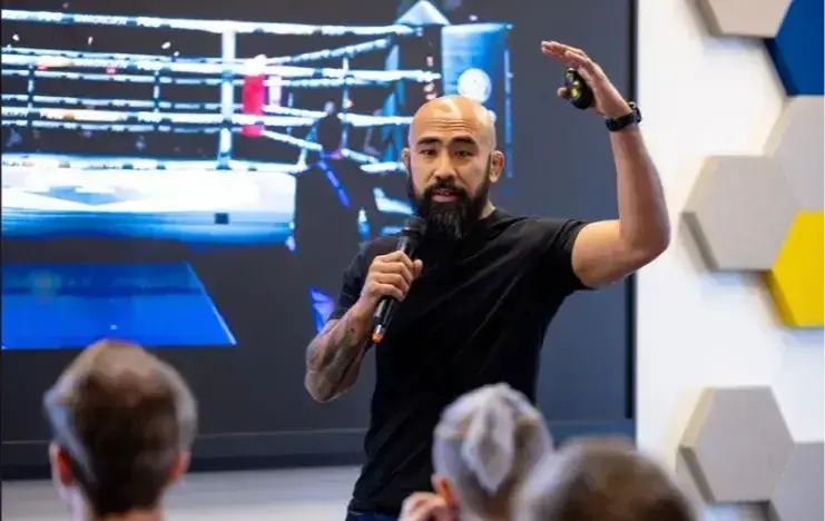 Chris Romulo speaking to students in a college gym during a resilience program