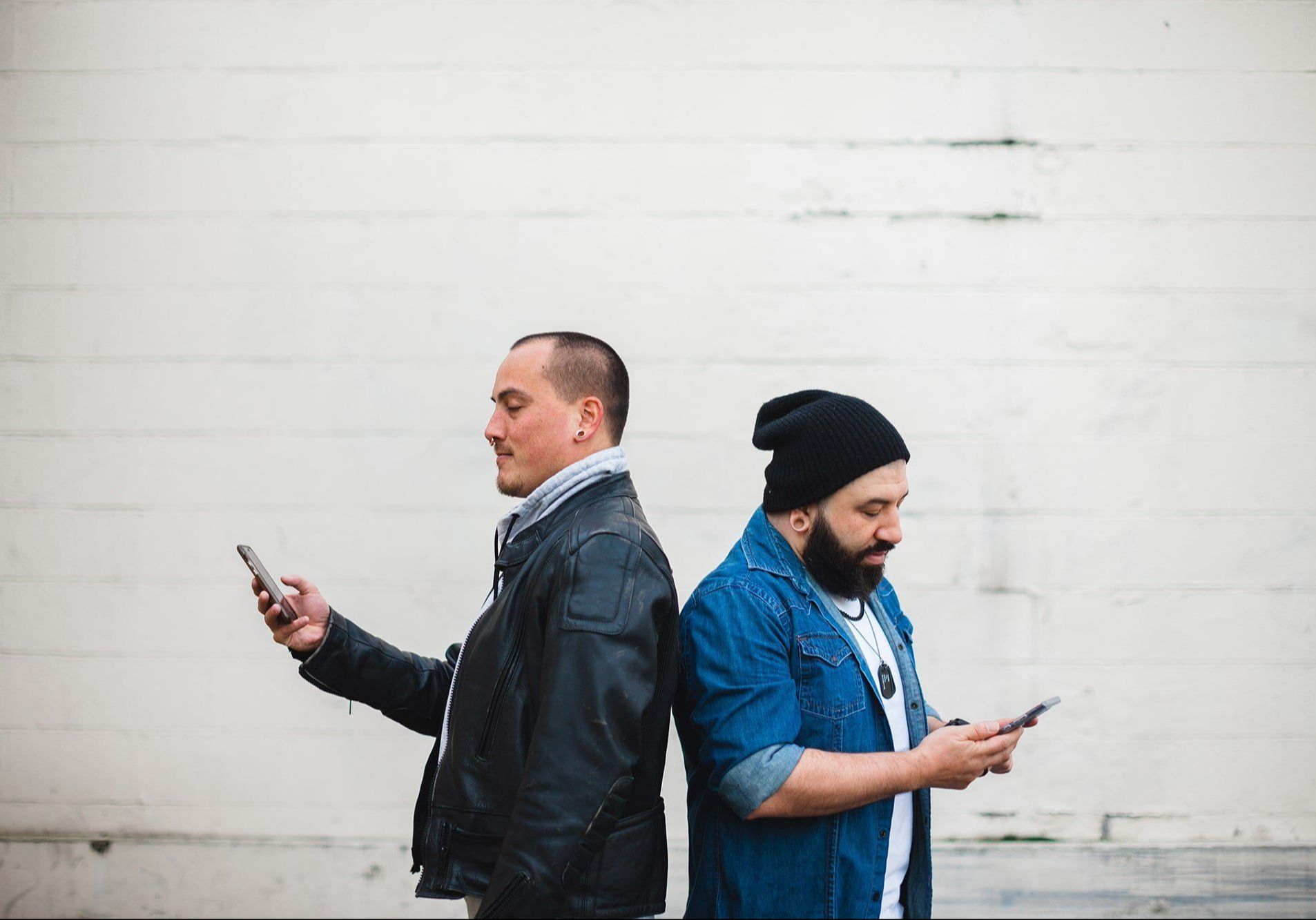Two people standing back to back with phones