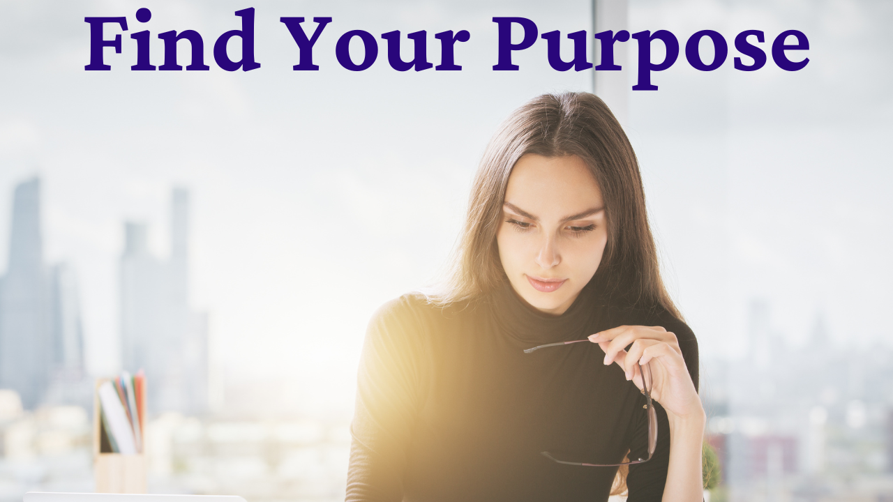 Woman sitting at a desk with city buildings visible in the background, wearing a black turtleneck and holding eyeglasses while focused on reading — symbolizing introspection and purpose discovery in the ‘Find Your Purpose’ module.