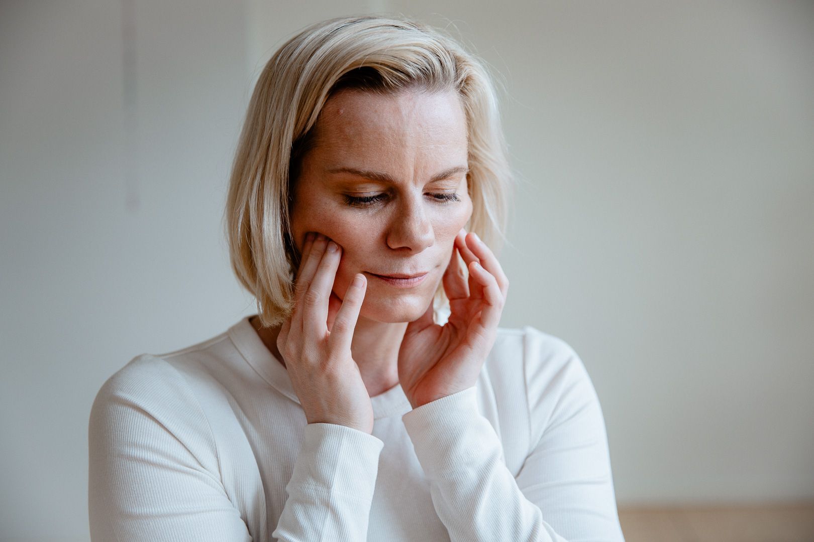 Frida Trönnberg sitter på yogamatta framför en laptop med en bäckenmodell bredvid sig – undervisar online om spänd bäckenbotten, vulvodyni, underlivssmärta och nervsystemets roll i läkning.