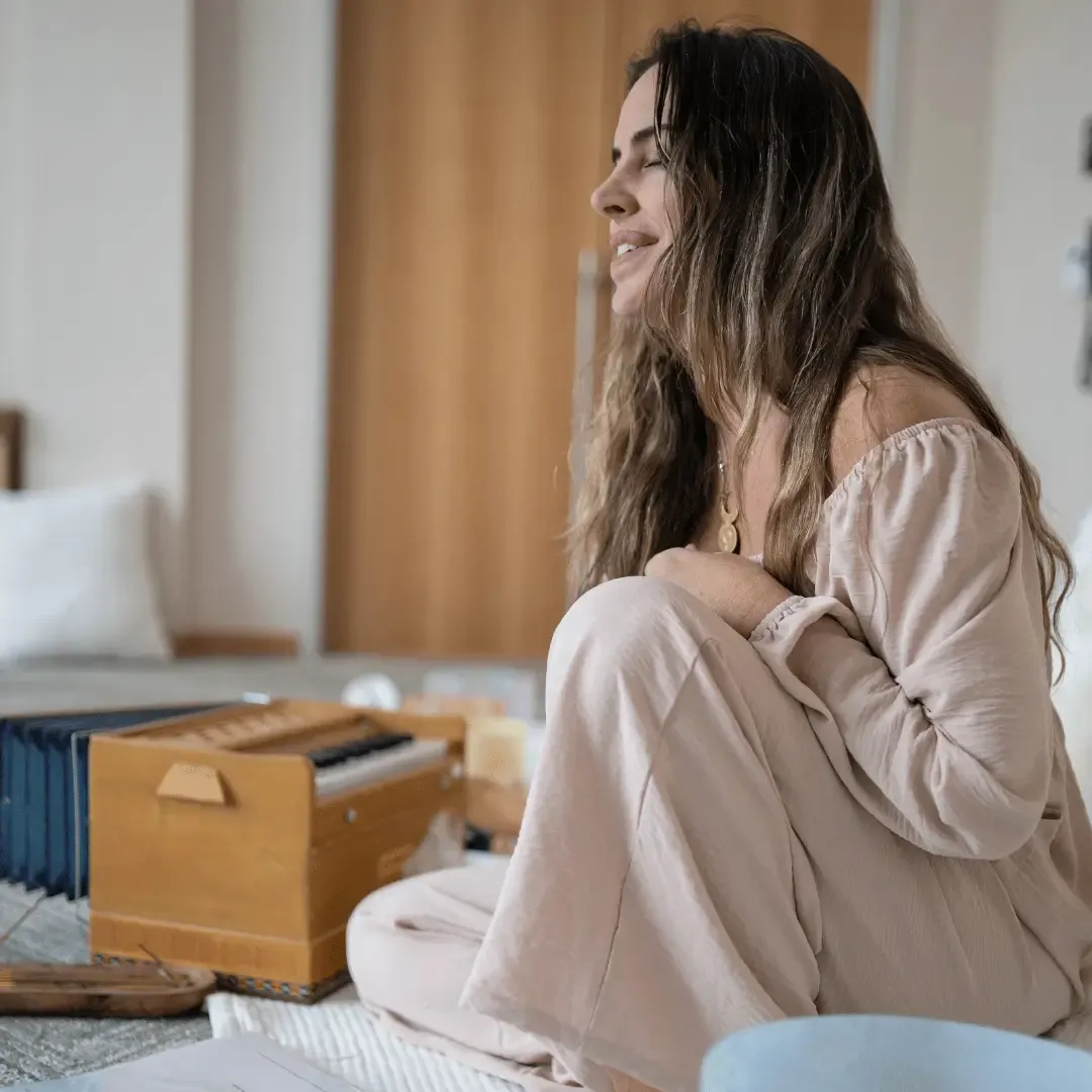 Fotografía de Sarah MacMillan sosteniendo un cuenco alquímico cristal con su alumna adelante sentada en pose de meditación