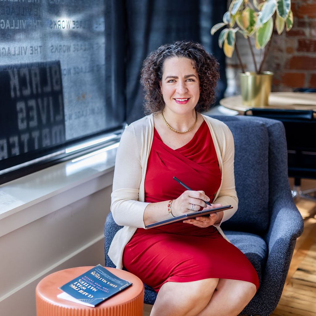 Author Erica Mattison seated writing with her career clarity book on a table next to her