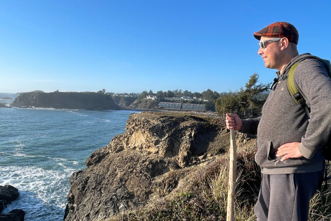 Man stands atop lookout point enjoying the expansive ocean view