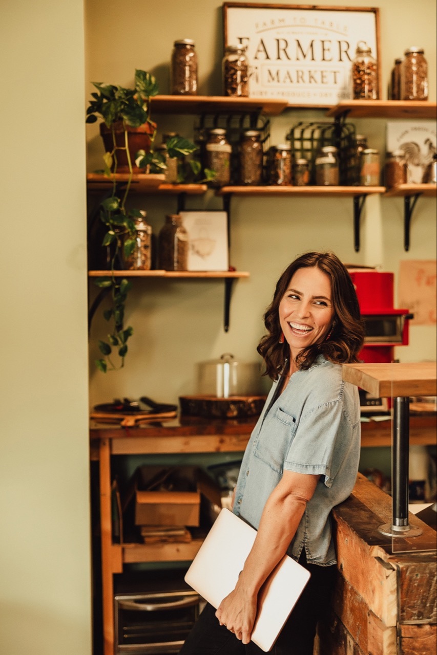 Lacy Davidson Ferguson standing in a kitchen holding a notebook and smiling