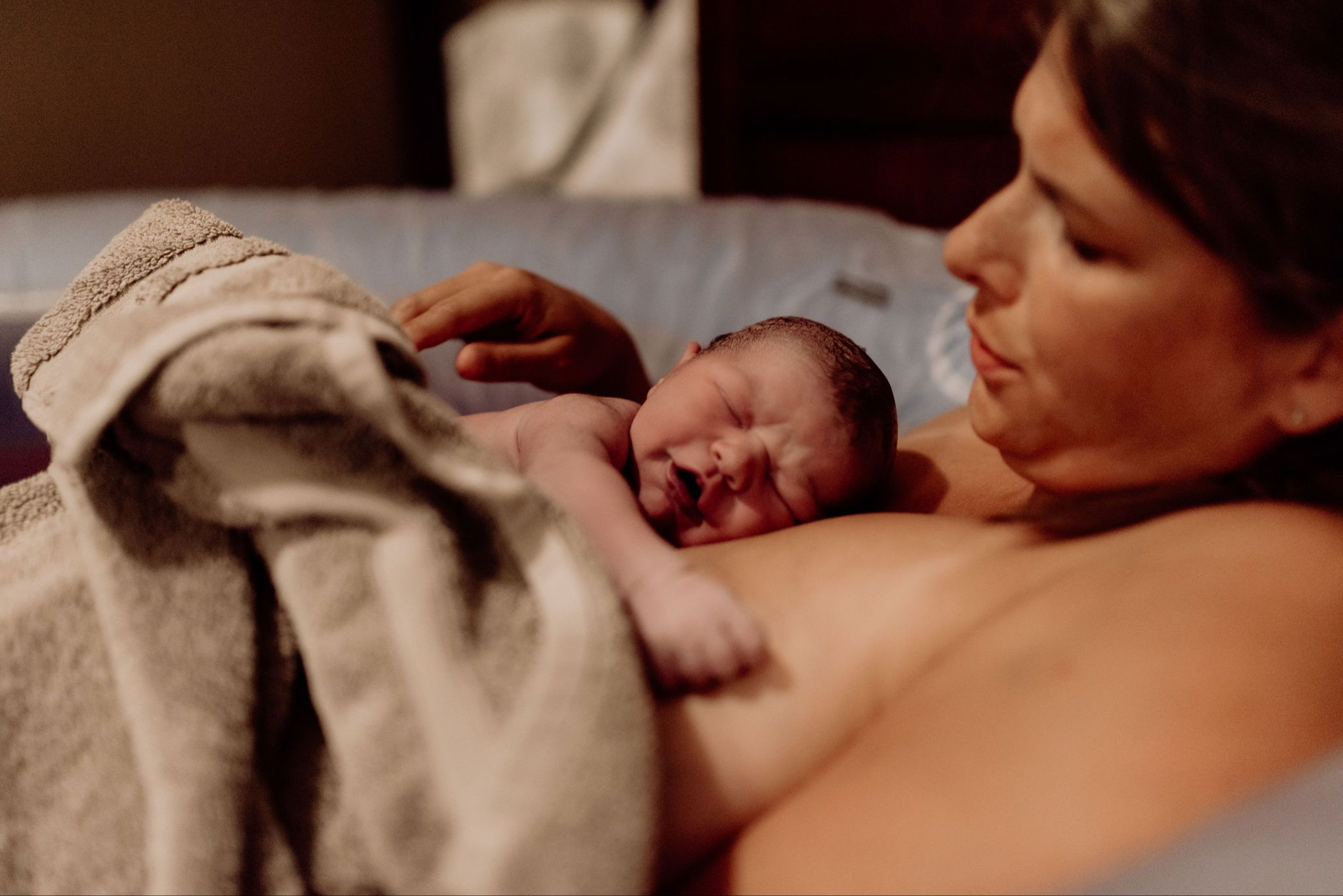 Mother holding newborn baby skin to skin after homebirth