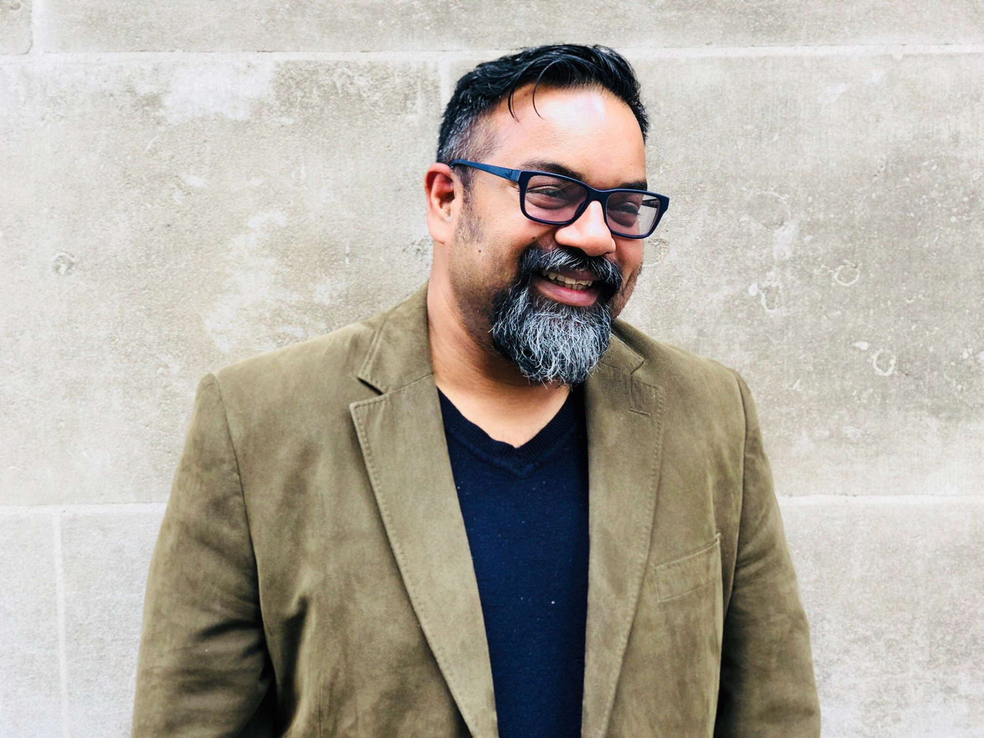 A photograph of Atif Choudhury. He is looking away from the camera and smiling.