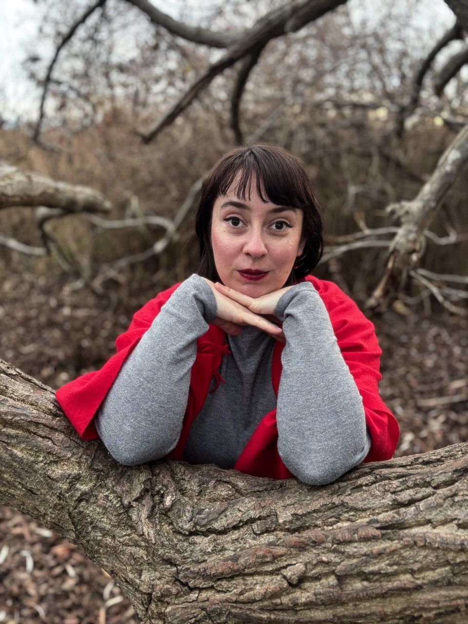 Sophie, founder of Embodied Sacred Feminine Wisdom, wearing round sunglasses, a black leather dress, and a blue top, with brown hair styled with bangs.