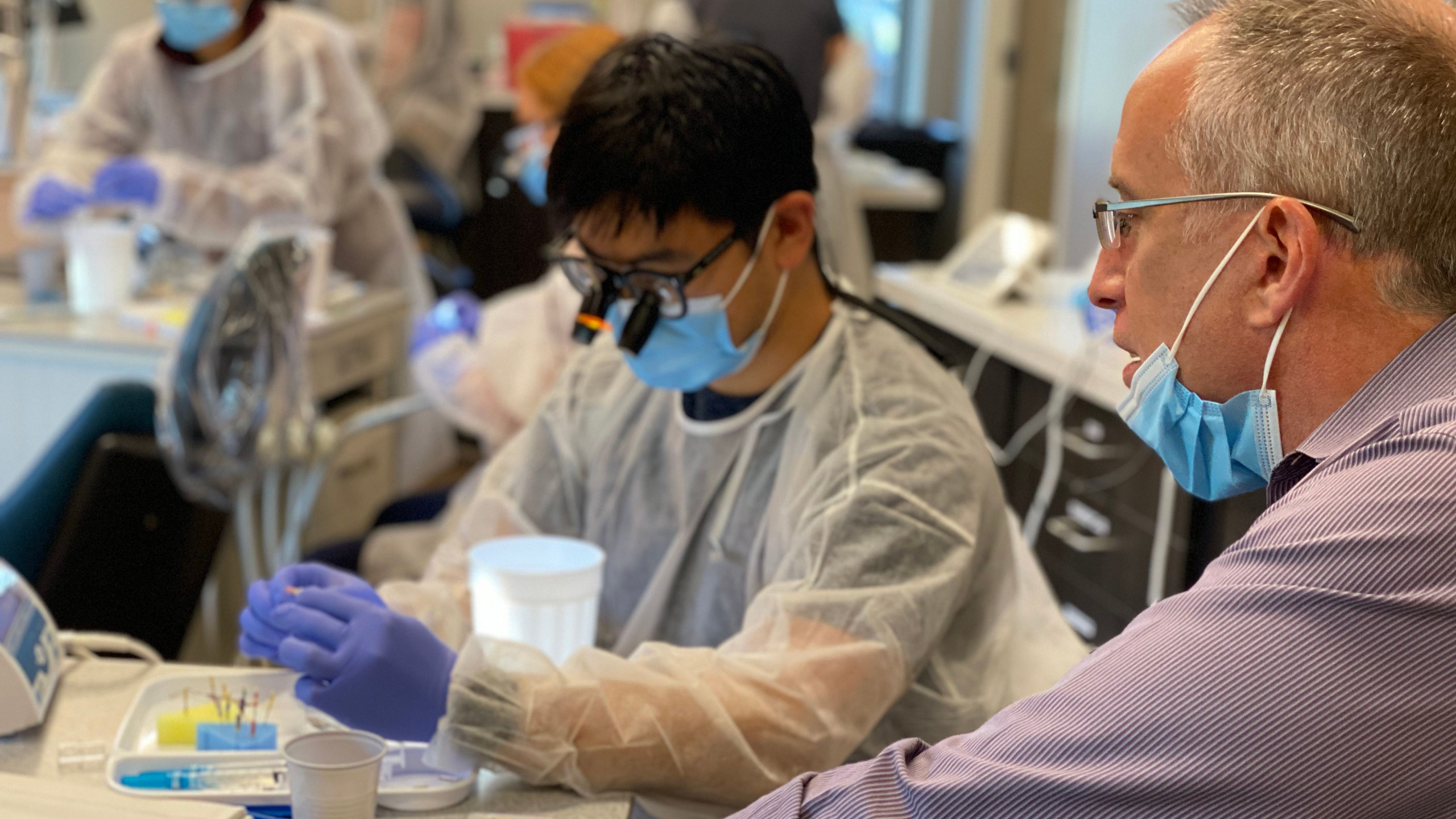 Dr. Nicholas teaching dentists during Efficient Surgical Extraction course on a live patient while students extract teeth
