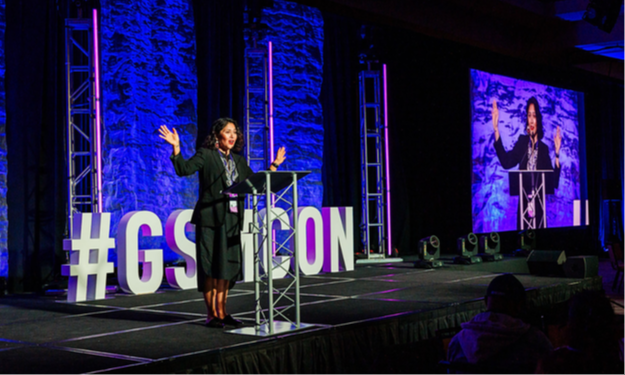 Presenter onstage in front of large #GSMCON letters
