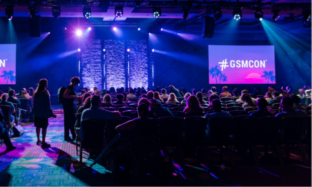 Audience seated facing the GSMCON's mainstage, with dramatic color lights. 