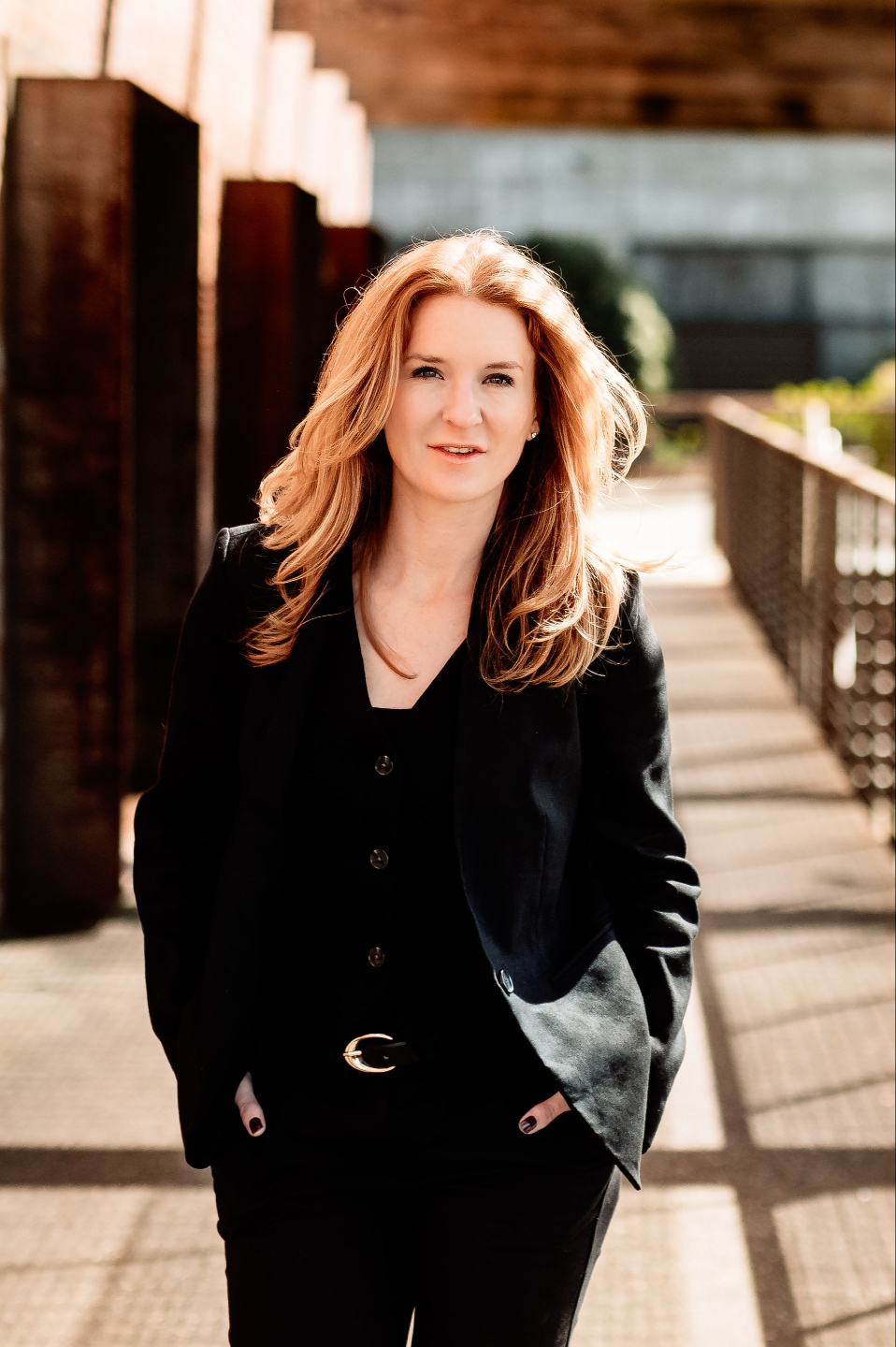 Rebecca Kase in black top and black pants sitting on a chair inviting contact to thrive in life and business