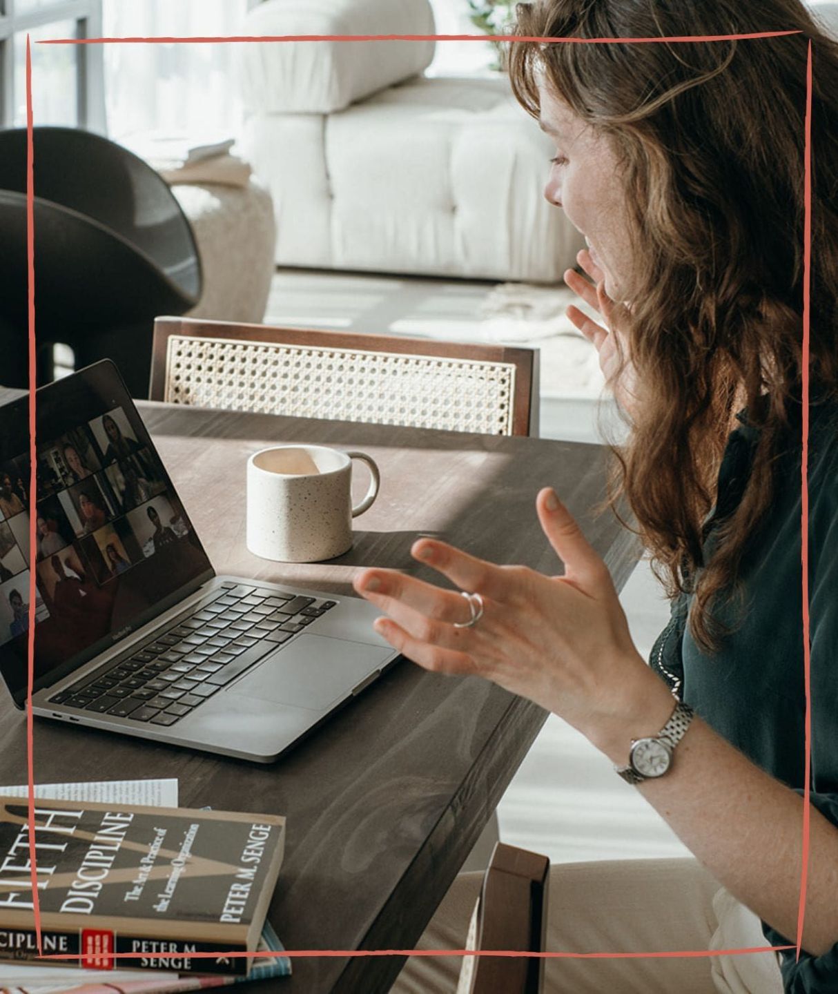 Someone wirting in a notebook while also look at another book. A laptop and coffee mug are on their table.