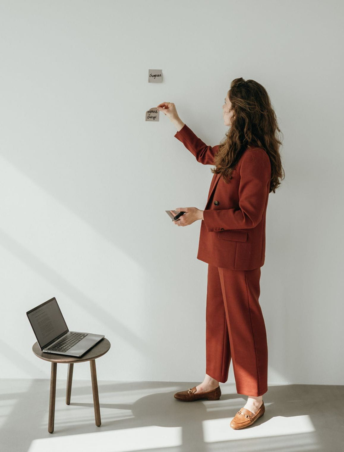 A person sits on a rock, gazing into the distance, with clouds overhead and three birds flying in the sky.