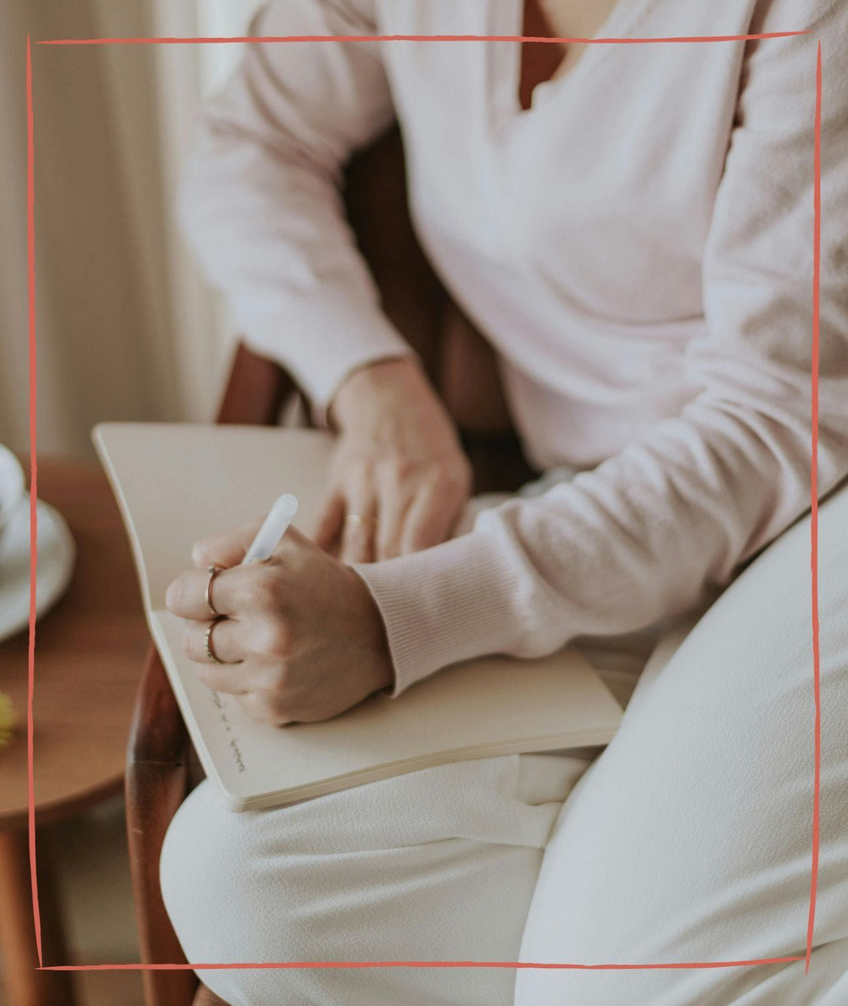 A woman with wavy hair in a white shirt and brown pants walks through a grassy field, surrounded by greenery and wildflowers.