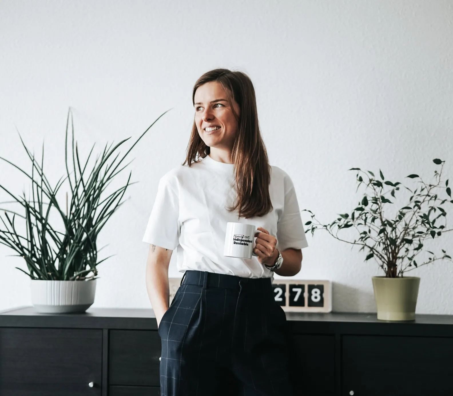 Photo de Janice Kerschbaumer, en tenue sport chic, tenant une tasse à café.
