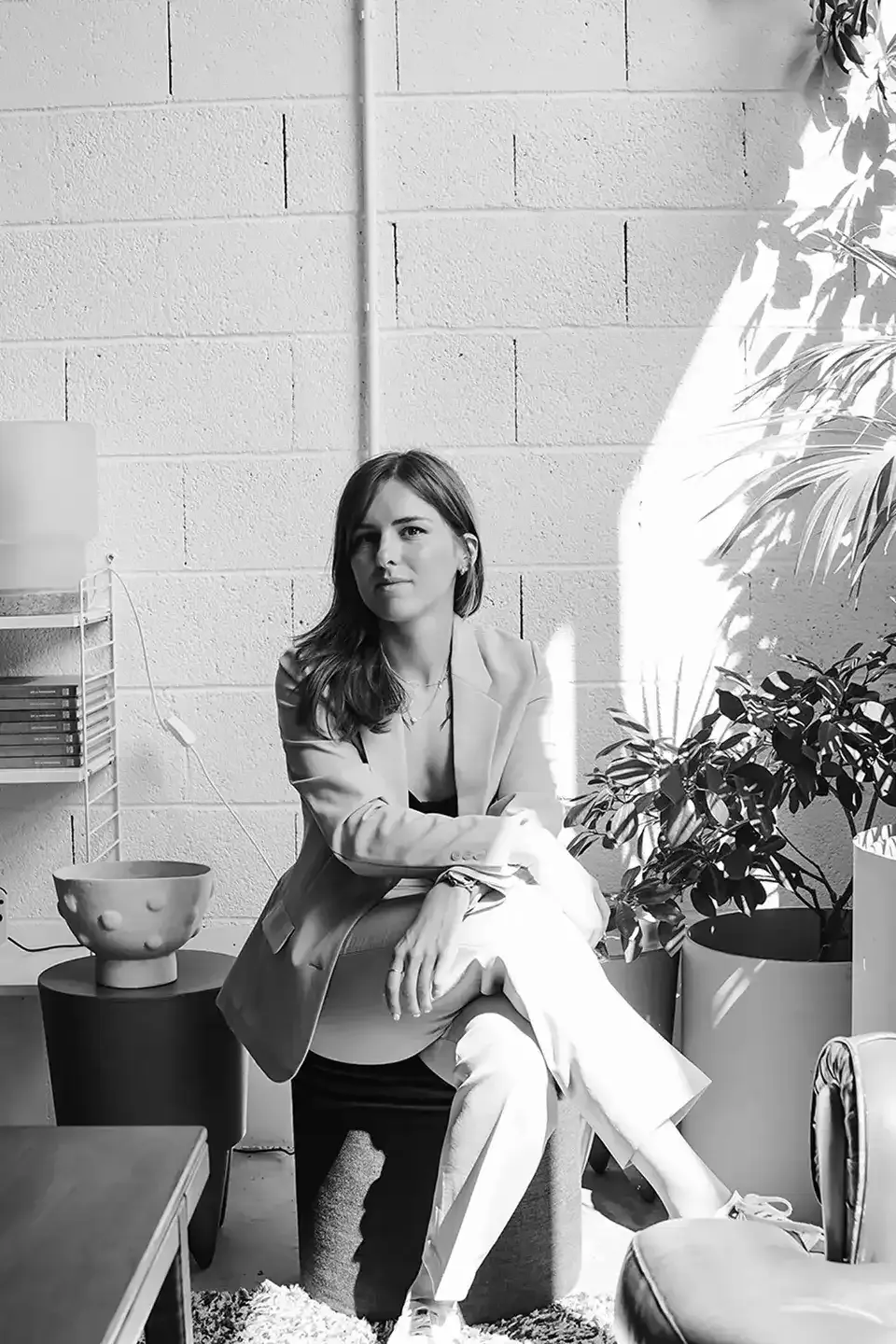 Janice en train de poser devant la caméra dans un environnement moderne avec de la verdure. Janice est en costume business. 