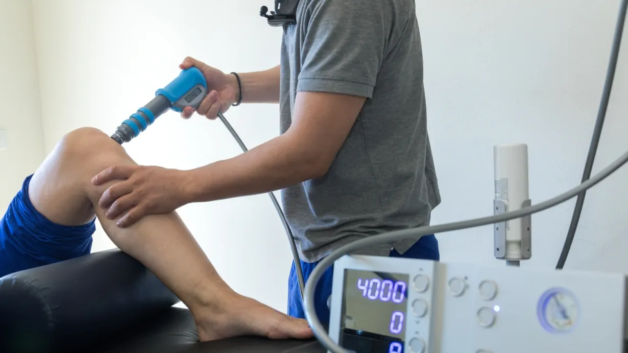 Clinician performing shockwave therapy on the knee joint