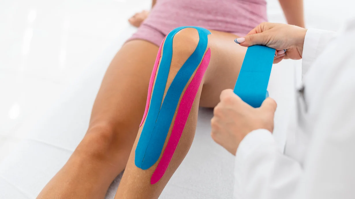 Clinician applying kinesiotape on a patient's knee
