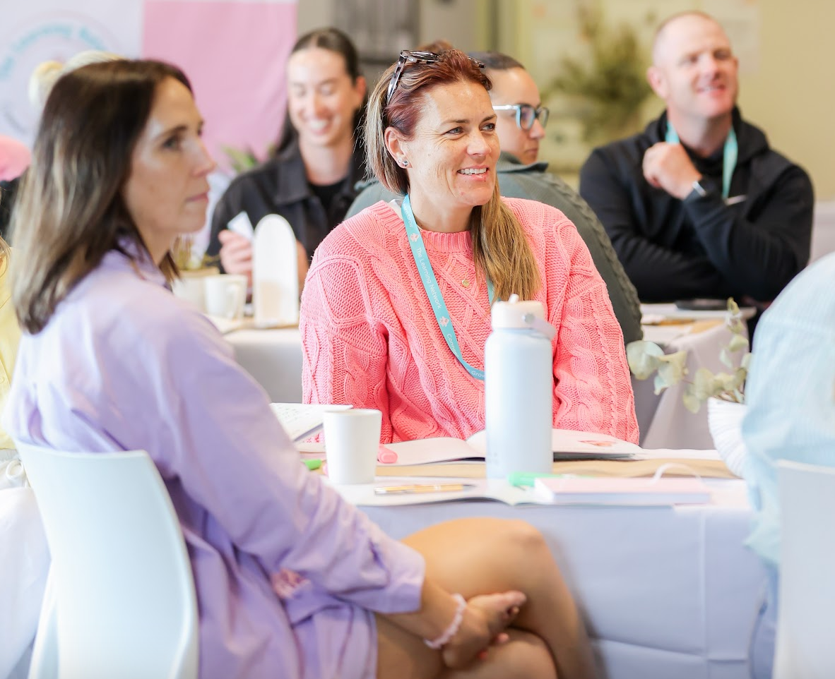 Image of Community and Family Studies (CAFS) and education coach Kelly Bell and others smiling while sitting at a table setting