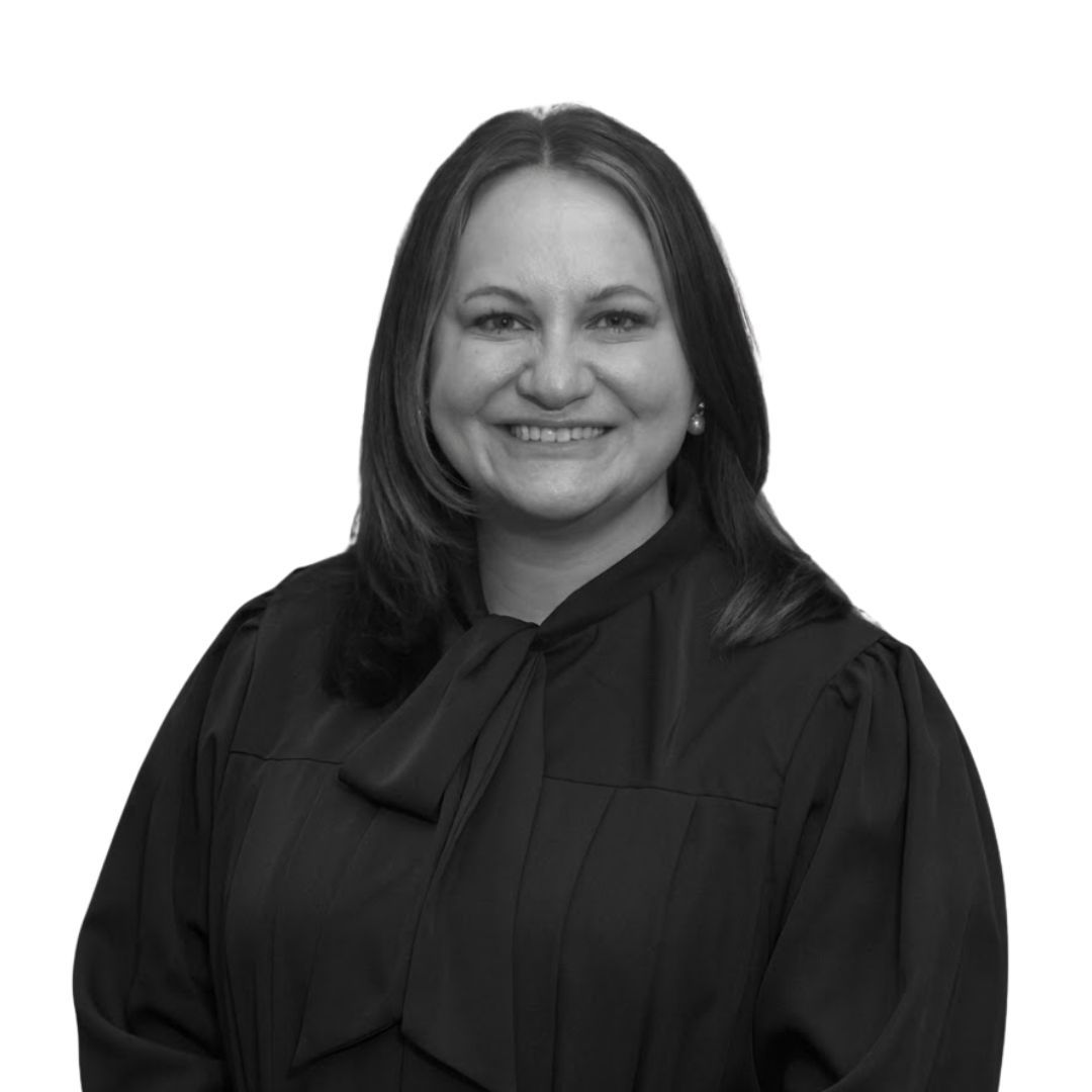 Smiling woman with straight shoulder-length hair wearing a dark blouse with a bow tie detail, facing forward against a plain background