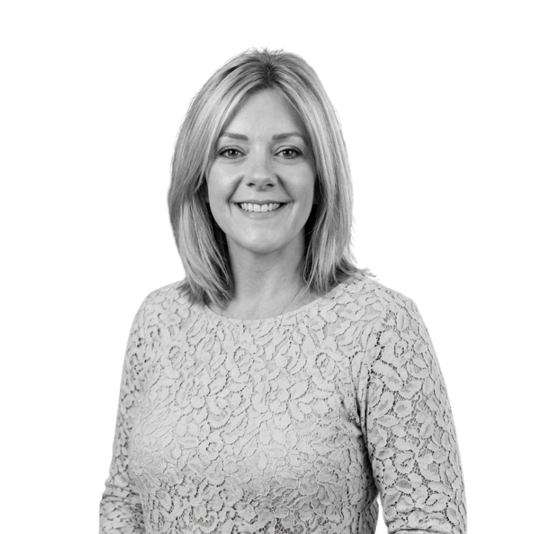 Professional headshot of a woman with shoulder-length hair, wearing a lace-patterned top and smiling at the camera