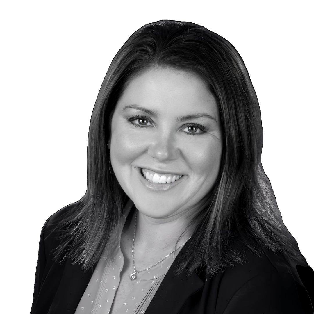 Smiling woman with shoulder-length dark hair wearing a blazer and blouse, facing slightly to the side against a plain background