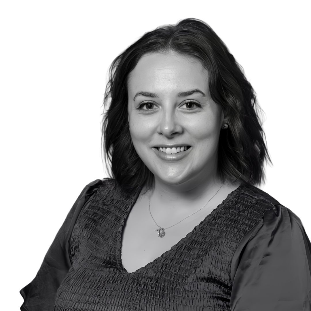 Smiling woman with shoulder-length wavy hair wearing a textured blouse and necklace, facing forward against a plain background
