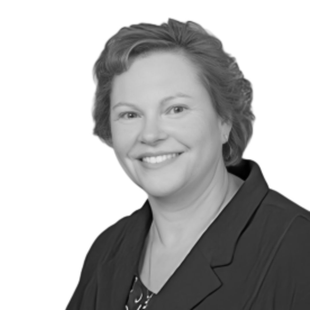 Smiling woman with short styled hair wearing a blazer, facing forward against a plain background