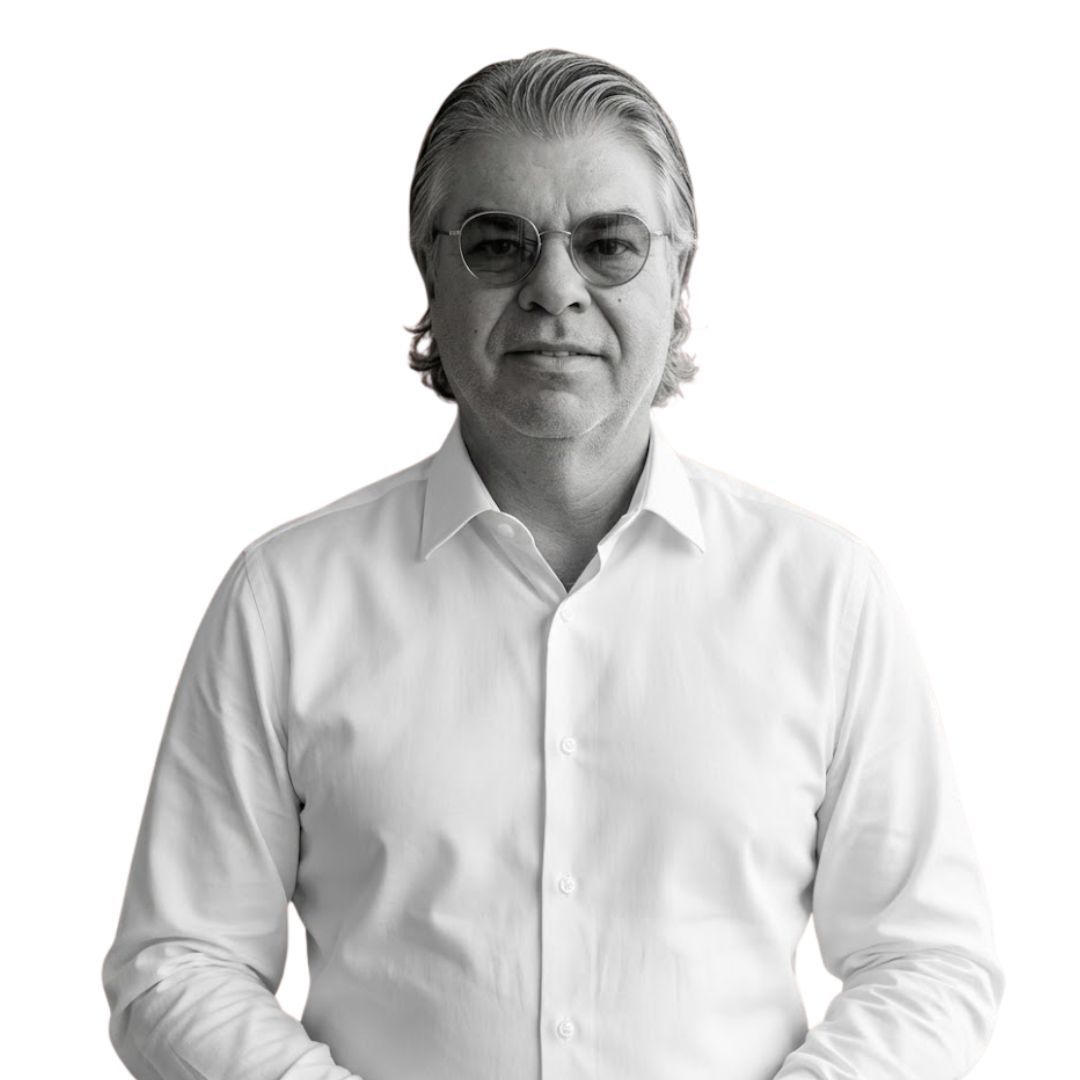 Middle-aged man wearing glasses and a white button-down shirt, with slicked-back hair, facing forward against a plain background