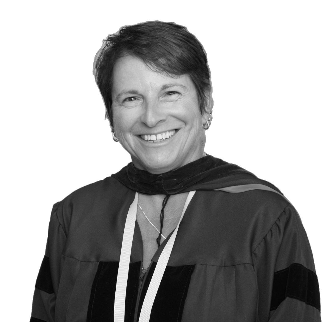 Smiling woman with short hair wearing academic regalia and a ceremonial gown, facing forward against a plain background