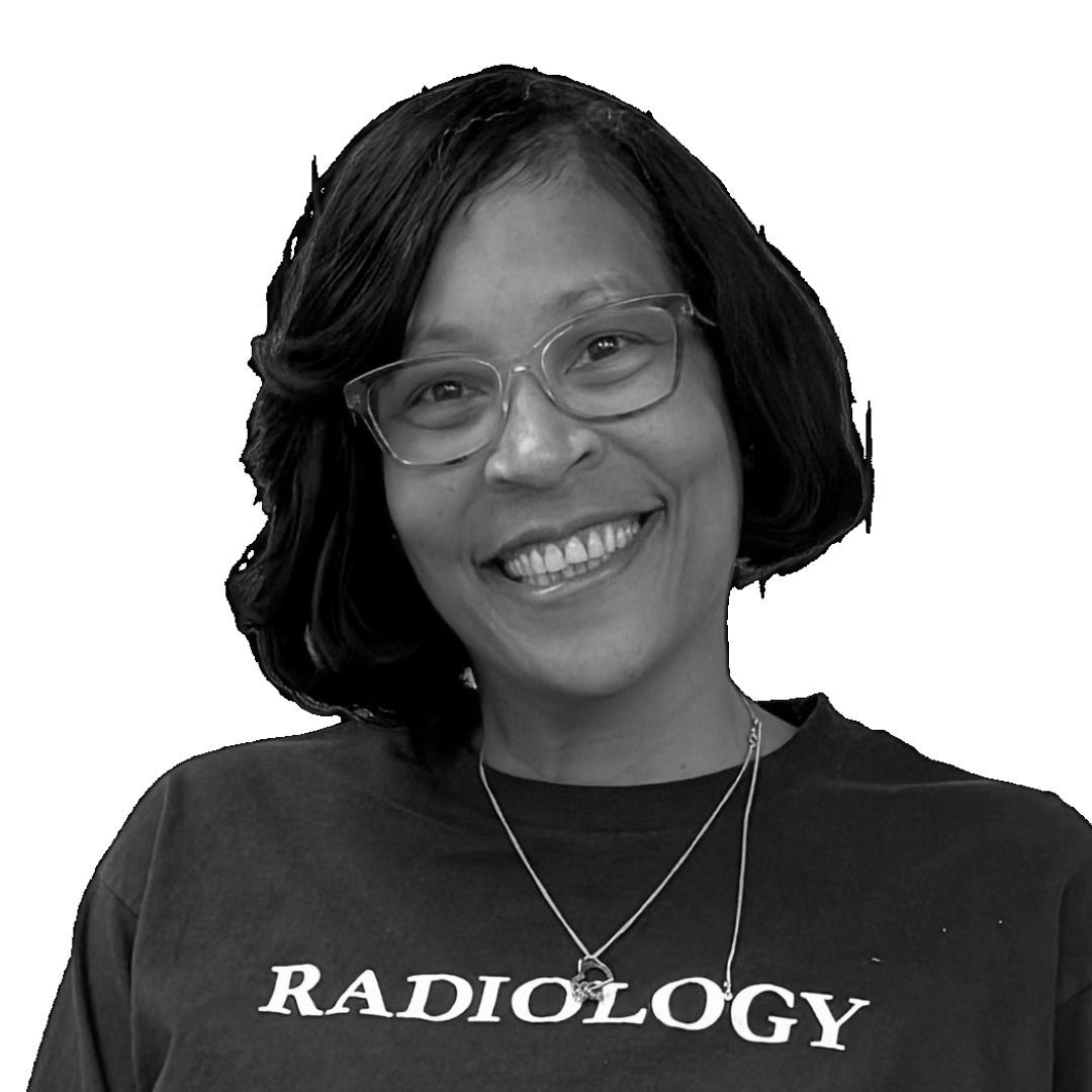 Smiling woman with short bob hairstyle wearing glasses and a ‘Radiology’ t-shirt, facing forward against a plain background