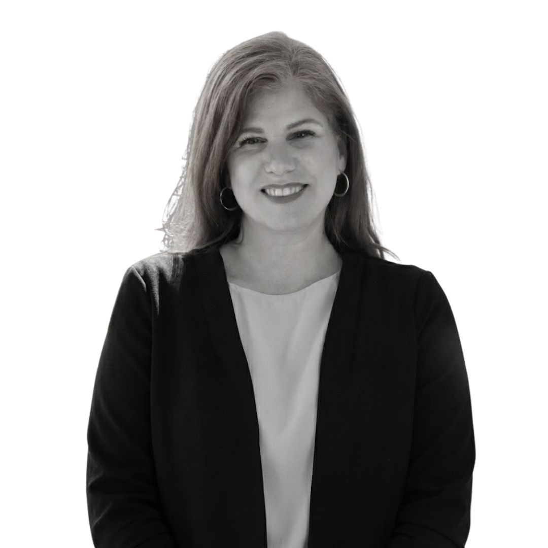 Smiling woman with shoulder-length hair wearing a blazer and light top, facing forward against a plain background