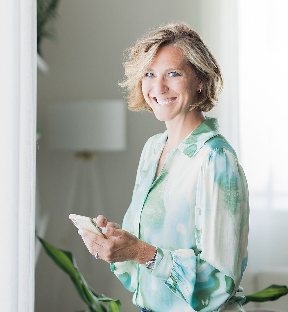 Ciara Stockeland looking at camera while holding mobile phone.