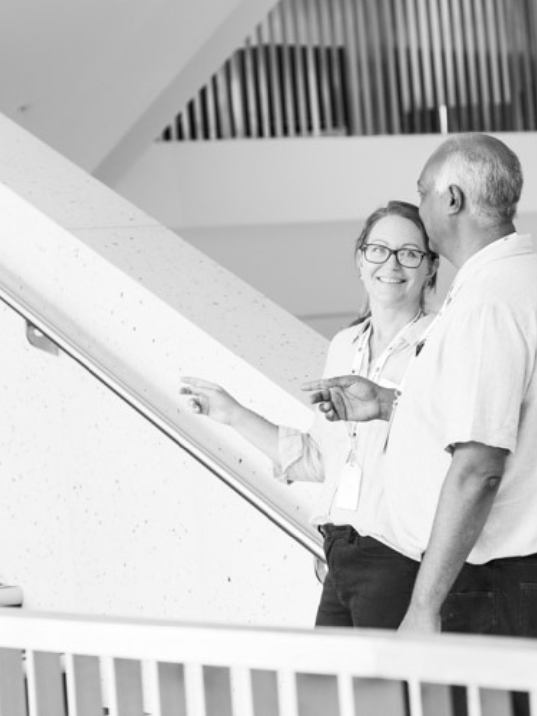 Two people walking through a warehouse one is holding a clipboard.