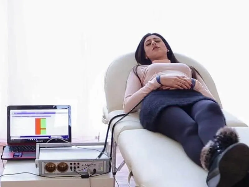 female client laying down on a bed relaxing in the clinic whilst connected to the bioresonance machine and receiving therapy tailored to her needs