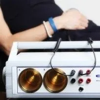 Client laying down relaxing whilst having bioresonance therapy by being attached by cables to a bioresonance machine