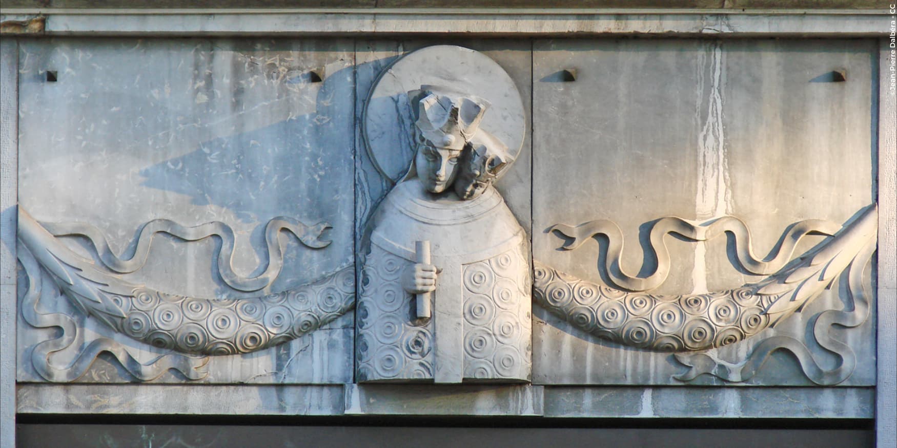 stenen reliëf in Ljubljana van een heilige figuur, geflankeerd door gestileerde zeedieren of draken