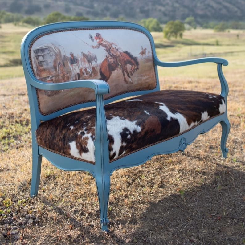 Love seat upholstered by sierra with old cowboy print on seat back, cowhide seat and painted in turquoise