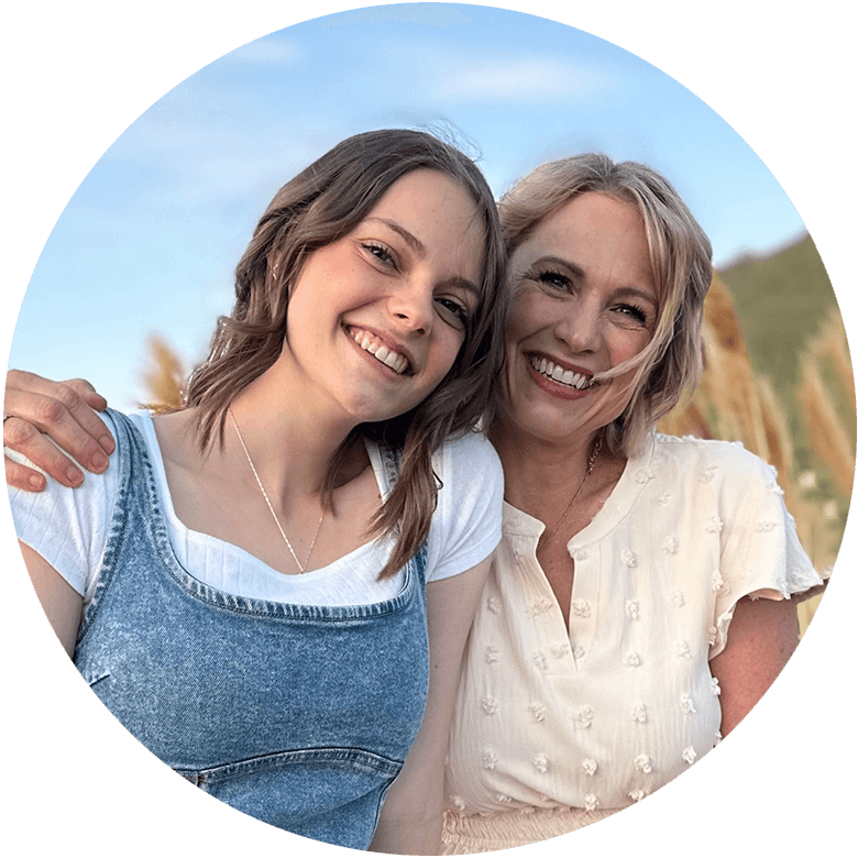 Steph Chaffee and young daughter embracing and smiling together in a field with blue sky behind them, symbolizing growth and a close bond