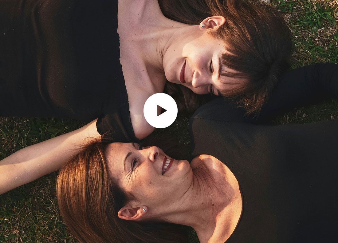 Video preview with image of mother and daughter laying in the grass together smiling