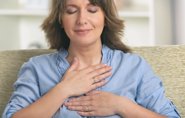 A woman practices Reiki with two hands on her heart. 