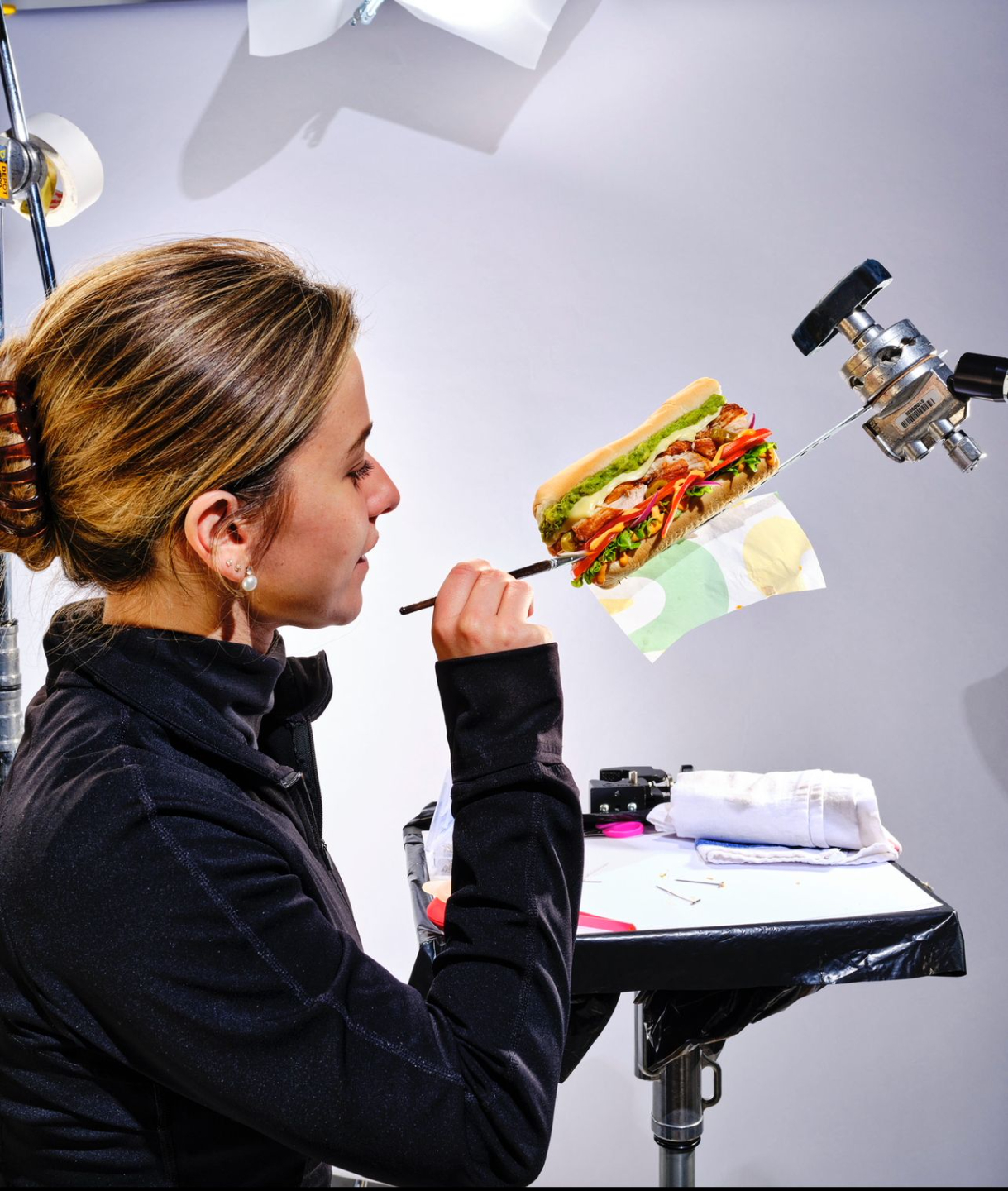 Food stylist adjusting a sandwich on a studio set during a food styling shoot