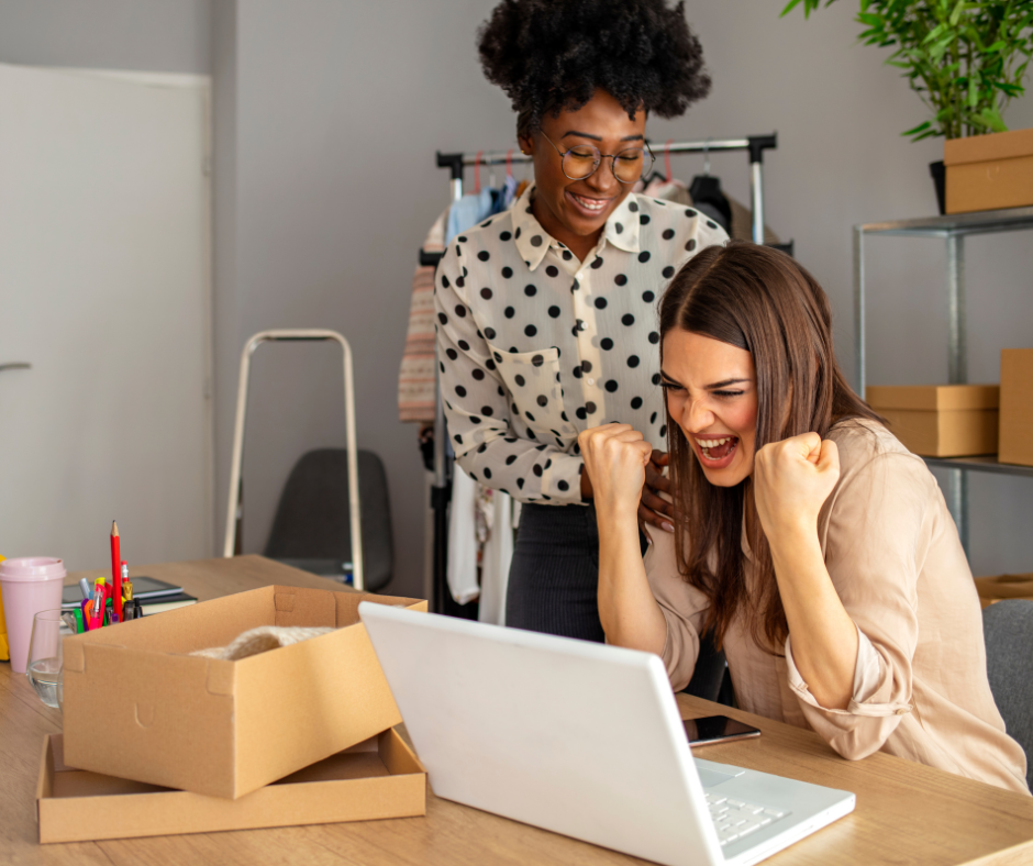 Women excited and celebrating together at a laptop