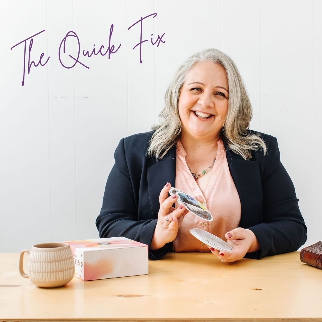 Nicki Kuurman sitting a desk shuffling oracle cards facilitating The Quick Fix - LIVE