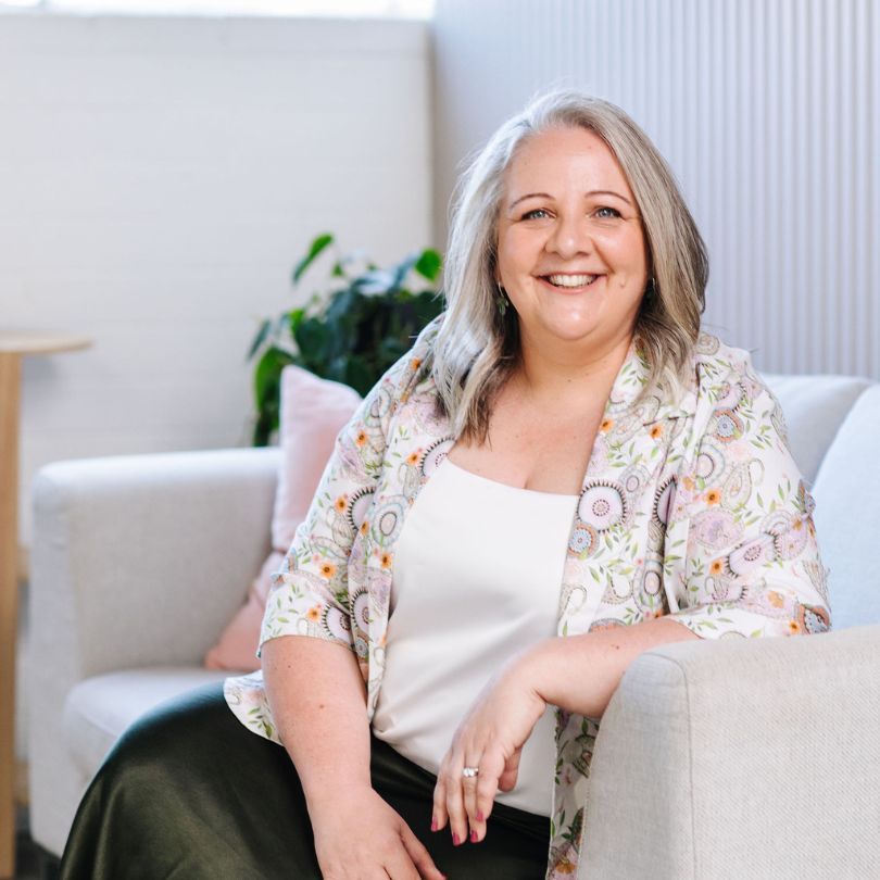 Nicki Kuurman sitting on a sofa, smiling to camera