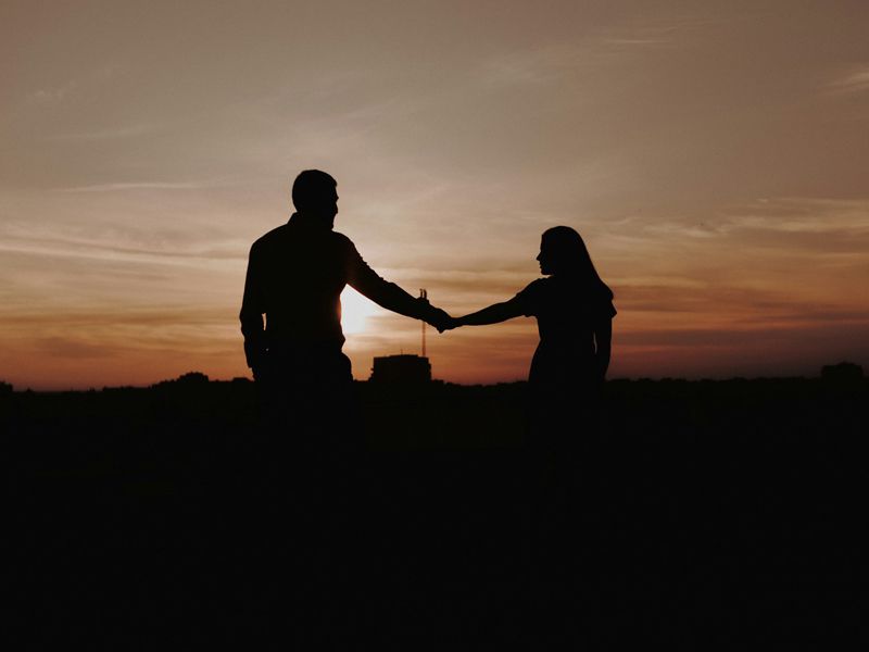 Silhouette of a man and woman reaching out to each other at sunset, symbolising reconciliation, connection, and rebuilding trust in relationships.