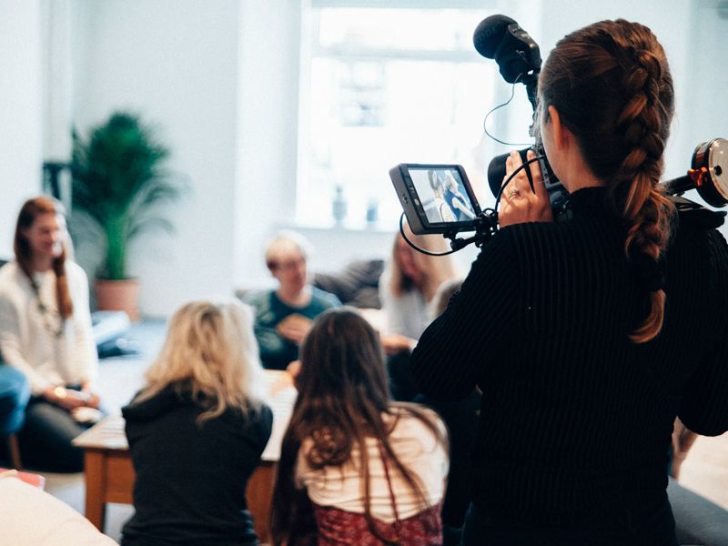 A confidence coach helping a small group improve public speaking and performance skills during a workshop.
