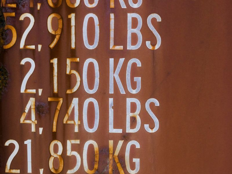 White weight and measurement markings displayed on a rusty surface, symbolising progress tracking, self-awareness, and letting go of comparison - Retrained Minds Hypnotherapy.